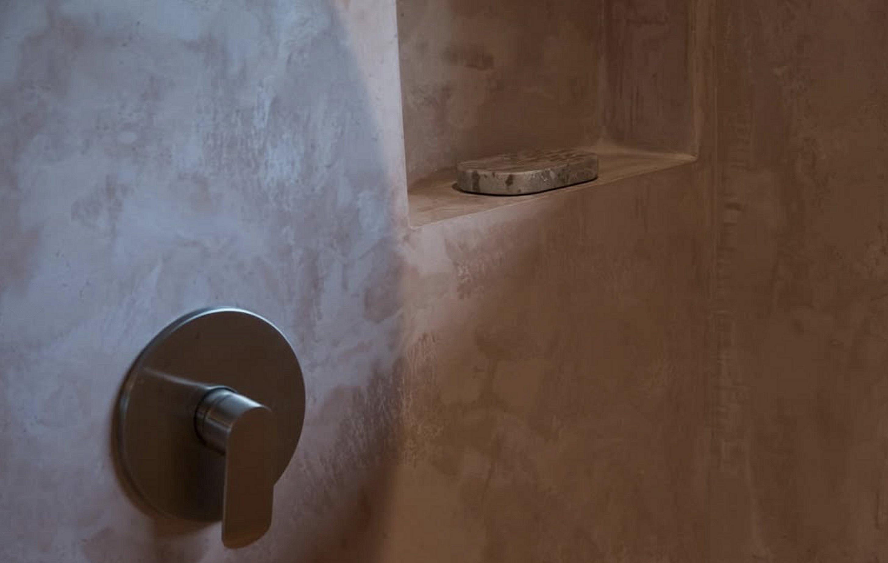 Hand-troweled microcement shower with a carved niche and natural stone soap dish, a Taino Builds specialty finish in Costa Rica